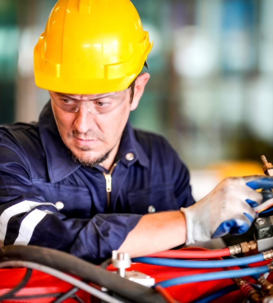 Male technician programs a robot arm with a digital tablet and assembly robot in a factory. Apprentice engineers programming robots in factory.